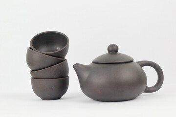 A Chinese black ceramic teapot and teacup isolated on a white background.