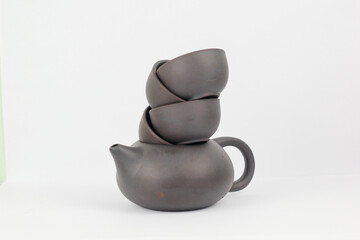 A Chinese black ceramic teapot and teacup isolated on a white background.