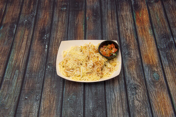 Cardboard tray for home delivery with cheese covered nachos and a black jar with pico de gallo to accompany