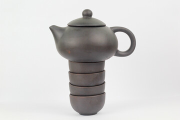 A Chinese black ceramic teapot and teacup isolated on a white background.