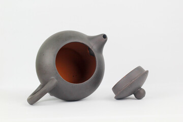 A Chinese black ceramic teapot and teacup isolated on a white background.