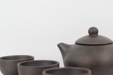 A Chinese black ceramic teapot and teacup isolated on a white background.