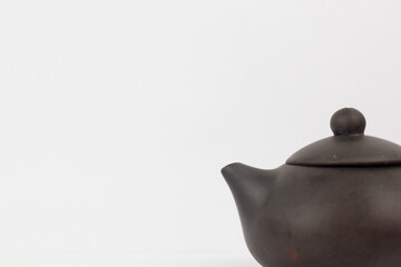 A Chinese black ceramic teapot and teacup isolated on a white background.