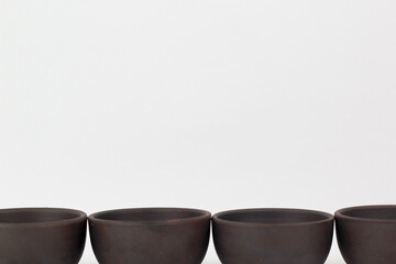 A Chinese black ceramic teapot and teacup isolated on a white background.