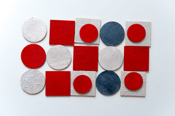 painted silver gray, red, and pearl white laser cut wooden plywood shapes, loosely arranged on a...