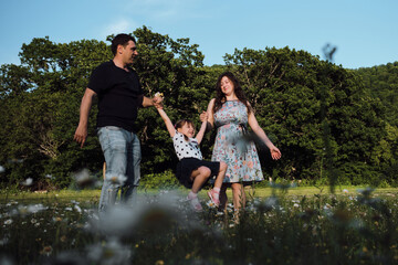 Nice European Caucasian family. Young happy family walks in park on warm summer day. Father and...