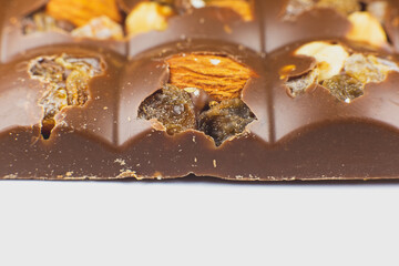 Milk chocolate bar with nuts, dried fruits and  raisins background texture. Close up, macro photo.