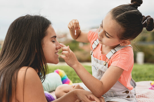Cute little girl making up her big sister - Teenage girl enjoy day outdoor with little sister - Family love