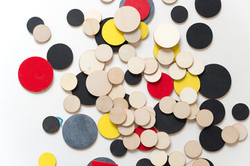 laser-cut plywood circular shapes hand painted in red, yellow, silver black, and flat black with some untreated pieces loosely arranged on white - photographed from above in a flat lay style