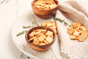 Bowls with tasty crackers on light background
