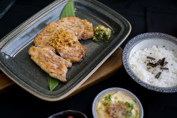Pork Chop Kurobuta Steak set with rice, salad, miso soup, tamagoyaki and kimchi on black background - Japanese food style