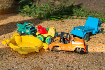 Children's plastic toys green end yellow car, shovel, red bucket, green ball with yellow sand on the beach by sea