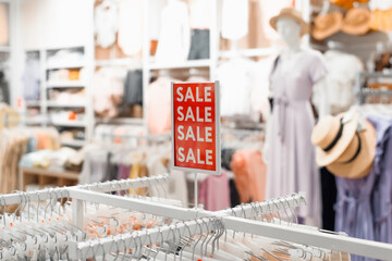 Sale in the women's section of a clothing store. Red sign with the inscription Sale, discount in the shop, blurred background. Black friday, sale concept