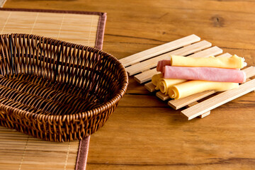 Ham and cheese with empty bread basket on breakfast table.