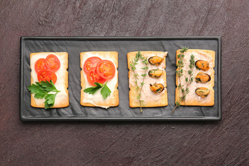 Tray with different crackers on dark background
