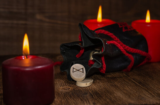 The rune Dagaz means Day. The rune fell out of an antique leather bag against a background of red candles. Selective Focus