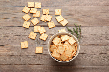 Bowl with tasty crackers on wooden background