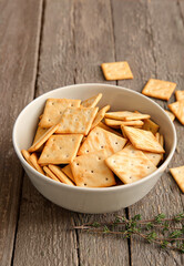 Bowl with tasty crackers on wooden background