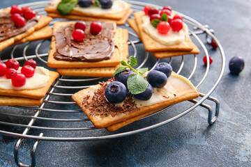 Tasty crackers with berries on color background, closeup