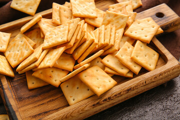 Board with tasty crackers on table, closeup