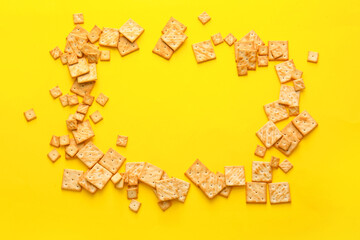 Frame made of tasty crackers on color background