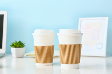 Takeaway cups for coffee on table near color wall