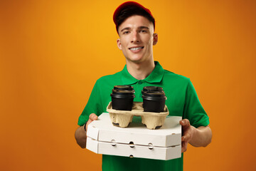 Happy young delivery man holding pizza box against yellow background