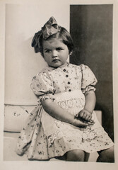 Germany - CIRCA 1930s: Portrait of small girl sitting in studio. Vintage archive Art Deco era photo