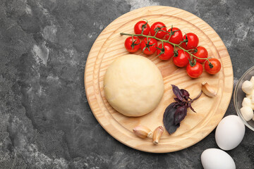 Board with dough and ingredients for preparing pizza on grunge background