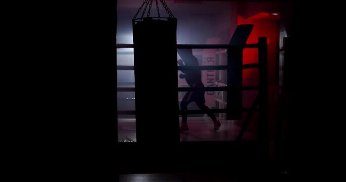 A boxer boxing with a shadow draws quick punches in a semi-dark ring with a backlight. Videos for motivation, goal achievement, success
