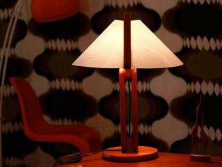 A vintage modern desk lamp from the 60s made out of tak wood standing on a desk isolated on white...