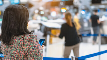 Back view of airline passenger wear face mask to prevent Corona virus (Covid-19) wait to check in counter in airport with staff wear face mask. New normal concept of travel after Covid-19 pandemic.