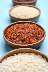 Bowls with different types of rice on color background, closeup