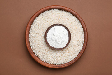 Bowls with flour and raw rice on color background