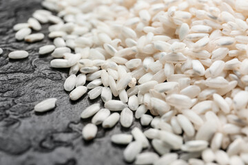 Heap of raw rice on dark background, closeup