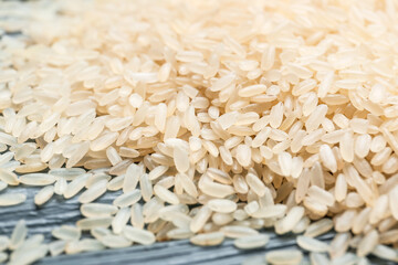 Heap of raw rice on dark wooden background, closeup