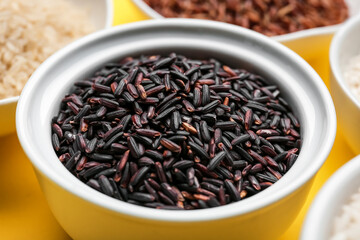 Bowl with black wild rice on color background, closeup