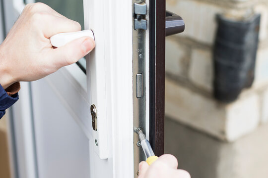 Handyman checks door lock with a key in front door. Checking lock for operability.