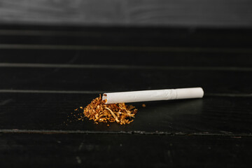 Cigarette with tobacco on dark wooden background
