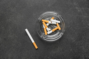 Ash tray with cigarettes on dark background