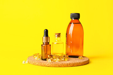 Bottles of fish oil and capsules on color background