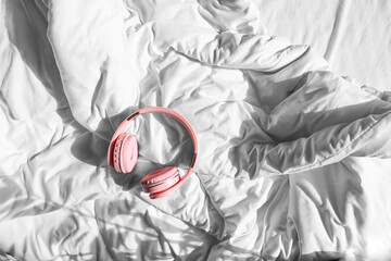 Modern headphones on bed in room