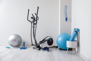 Different sports equipment and fitness balls near light wall