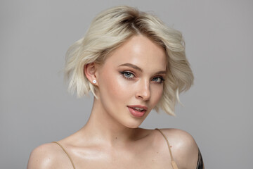 Portrait of a beautiful blonde girl with a short haircut. Gray background. - obrazy, fototapety, plakaty