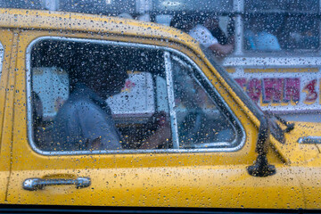 Raindrops falling on glass, abstract blurs - monsoon stock image of traditional yellow taxi of...