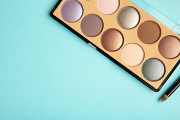 Professional makeup palette with brush on blue background.