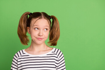 Fototapeta premium Photo of unsure tails hairdo little girl look empty space wear striped sweater isolated on green color background