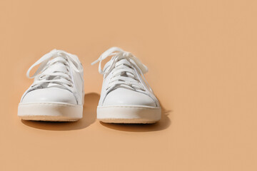 White female gumshoes or sneakers on a beige background. Copy space.