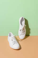 White female gumshoes on beige and green color background. Vertical format.