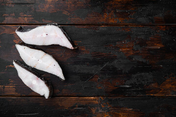 Steaks of fish and fillet of sea fish frozen, on old dark  wooden table background, top view flat...
